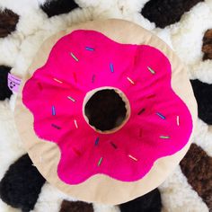 a pink donut pillow with sprinkles on it sitting on a black and white rug