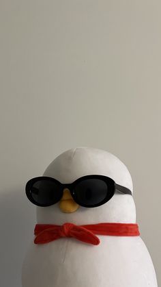 a stuffed penguin with sunglasses on it's head and a red ribbon around its neck