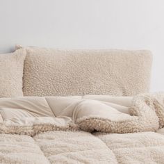 an unmade bed with fluffy blankets and pillows