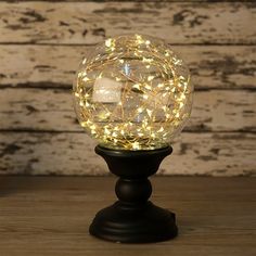 a glass ball with lights inside on a wooden table