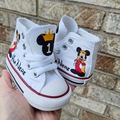 someone is holding up their white shoes with mickey mouse designs on the front and bottom