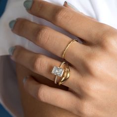 a woman's hand with two rings on it and a diamond in the middle