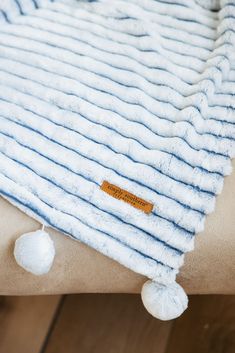 a blue and white blanket with pom - poms on the bottom is sitting on a wooden floor