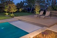 a backyard with a pool, deck and lawn furniture at night in the evening time