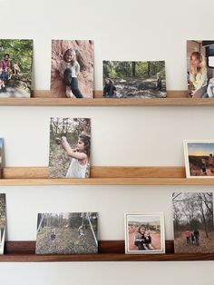 several pictures are hanging on the wall with wooden shelves above them, along with other family photos