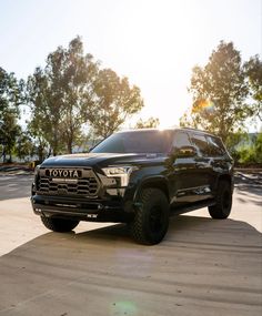 a black toyota pickup truck parked in a parking lot with the sun shining on it