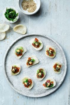 small appetizers are arranged on a platter next to bowls of seasoning