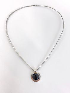 "Vintage Sterling Silver Wire Collar Necklace with Black Onyx Pendant - Classic and simple in design to go with any wardrobe - Sterling silver wire \"V\" shaped collar necklace with small hook closure - Floating pendant consists of a round black onyx bezel set in Sterling silver - Both pieces are marked \"925\" - The wire necklace is about 2mm gage and measures about 18\" all the way around (9\" on each side) - Pendant measures about .8\" x .8\" with a depth of .32 - Onyx stone measures about 15 Modern Onyx Necklaces With Polished Finish, Modern Onyx Necklace With Polished Finish, Elegant Oval Pendant Necklace With Black Enamel, Modern Black Oval Pendant Necklace, Modern Black Jewelry With Sterling Silver Clasp, Modern Silver Necklace With Black Enamel, Sleek Sterling Silver Jewelry, Black Oval Pendant Minimalist Jewelry, Minimalist Silver Onyx Necklace