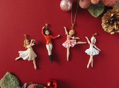 four figurines are hanging on a red wall next to christmas decorations and ornaments