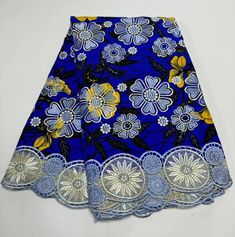 a blue skirt with yellow and white flowers on the bottom is sitting on a table