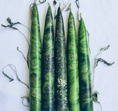 four green pea pods are shown on a white surface