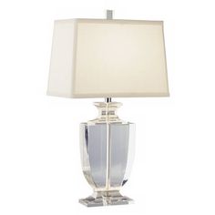 a clear glass lamp with a white shade on the base and a square light bulb