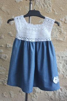 a dress made out of denim and crochet is hanging on a clothes rack