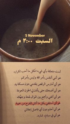 an open book with arabic writing on it next to a metal cup filled with liquid