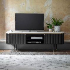 an entertainment center with a television and potted plants