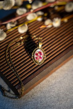 a necklace with an image of a flower on it sitting on top of a piece of wood