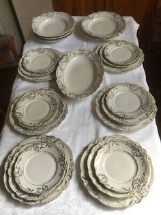 a table topped with lots of white plates and silverware on top of a cloth covered table