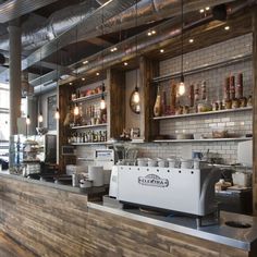 the interior of a restaurant with wood paneling and exposed ceiling beams, along with an espresso machine