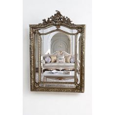 an ornate gold framed mirror hanging on the wall above a white couch and coffee table