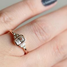 a woman's hand with a diamond ring on top of her finger and nail polish