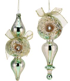 two glass ornaments hanging from strings on a white background, one with a flower and the other with a bow