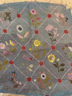 an old piece of cloth with flowers on it and squares in the middle that have been stitched together