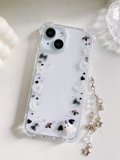 an iphone case with charms attached to it sitting on a table next to some beads