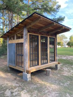 a small wooden building sitting in the middle of a field