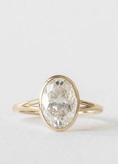 a gold ring with a white diamond in the center and a thin band around it