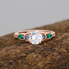 a close up of a ring on top of a rock with green and blue stones