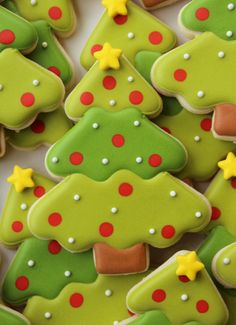 christmas cookies decorated with green, red and yellow icing are arranged in rows on a white surface