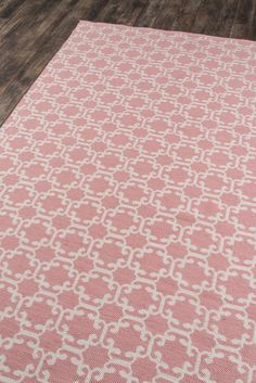 a pink and white rug on the floor in a room with hardwood floors, wood floors and