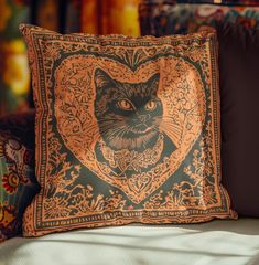 a black and orange pillow with a cat's face in the heart on it