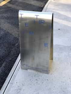 a stainless steel sign sitting on the side of a road