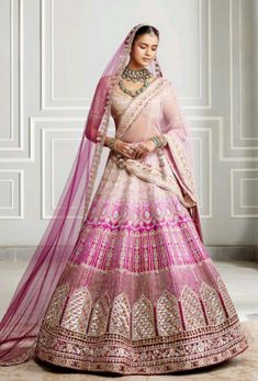 a woman in a pink and gold bridal gown posing for the camera with her hands on her hips