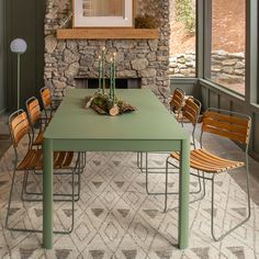 a dining room table with chairs and a stone fireplace in the back wall behind it