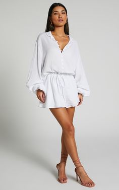 Turn heads in the Laylani Playsuit - V Neck Puff Sleeve In White. This playful and flirty playsuit is perfect for any casual occasion, with its A line shape and white cotton fabric that's both comfortable and chic. The v neck adds a touch of femininity, while the puff sleeves give it a trendy edge. Whether you're dressing up for a night out or keeping it cozy during winter, this long sleeve playsuit will have you looking effortlessly stylish wherever you go. So why wait? Go ahead and add this mu White Mini Length Jumpsuits For Beach, White Beach Jumpsuit With Relaxed Fit, White Mini Length Jumpsuits And Rompers For Vacation, White Cotton Beach Jumpsuits And Rompers, Summer Cotton V-neck Jumpsuit, White Cotton Jumpsuits And Rompers For Beach, Summer Cotton V-neck Jumpsuits And Rompers, White Relaxed Fit Jumpsuit For Vacation, White Mini Length Jumpsuits For Summer