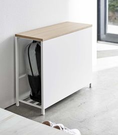 a white cabinet with a black bag sitting on it's side next to a wall