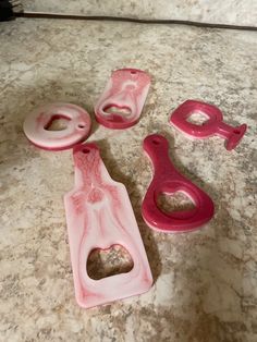 three pieces of pink plastic sitting on top of a marble counter next to each other