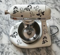 an old fashioned mixer with cartoon stickers on the front and sides, sitting on a marble countertop