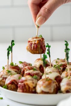 a person dipping some food on top of skewered meatballs with toothpicks