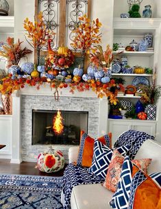 a living room filled with furniture and a fire place covered in fall leaves on top of a mantel