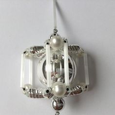 an ornament made out of glass with pearls and beads hanging from it's side