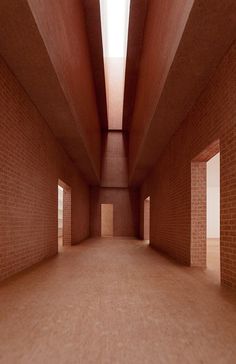 an empty hallway with red brick walls and light coming in from the windows on either side