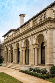 an old style building with columns and arches on the front, surrounded by greenery