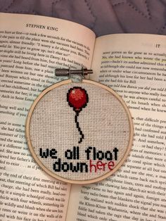 a cross stitch book with a red balloon on it and the words we all float down here