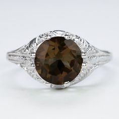 This vintage style ring features a round cut smoky quartz set in a sterling silver setting. The Art Deco style setting is beautifully crafted with curling filigree. The smoky quartz is a natural, earth mined stone. The ring measures 10mm across (north south) and 7mm from finger to top.Please note that colors can vary slightly depending on your monitor and display settings. The video features this setting with a peridot center. This version is also available in our shop. Sterling Silver Garnet Ring, Antique Engagement Rings Vintage, Vintage Style Art, Quartz Colors, Vintage Style Rings, North South, Sterling Silver Filigree, Green Amethyst, Natural Earth