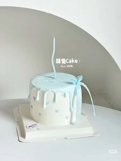 a white cake with blue icing sitting on top of a plate