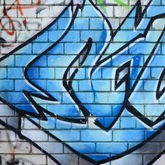 graffiti on the side of a brick wall with blue and white spray paint in it