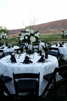 the table is set with black and white linens for an elegant wedding reception in the mountains